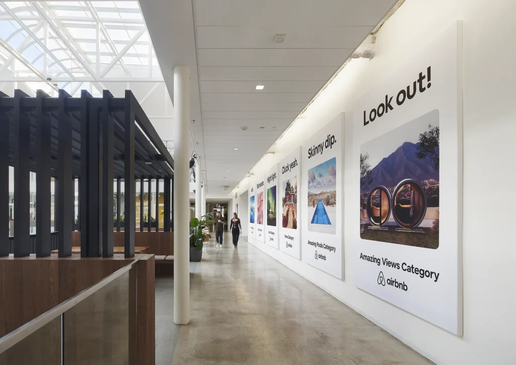 Bright, modern hallway at Airbnb headquarters with large textile stretch frames in corporate design on the wall