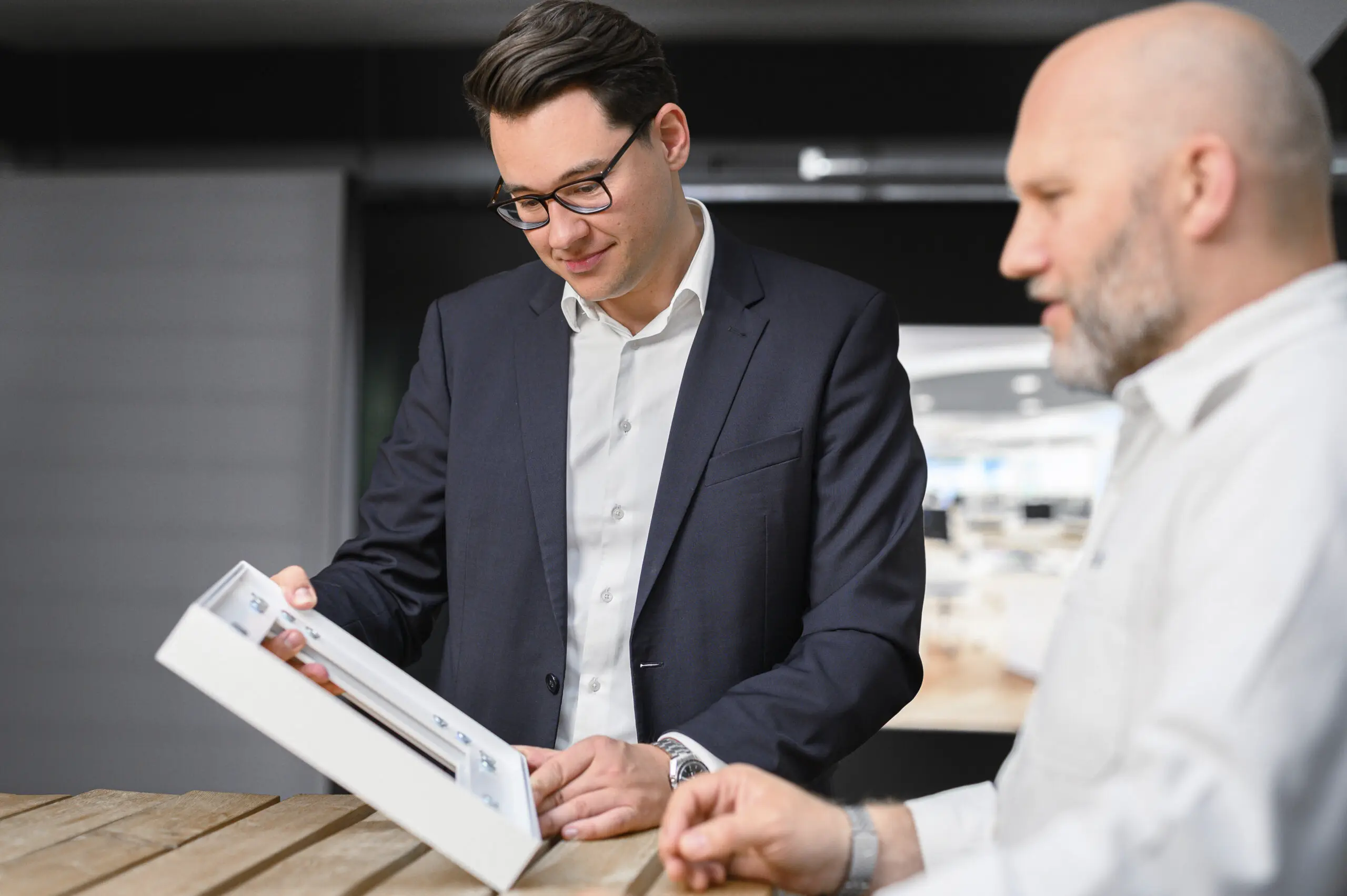 Zwei Geschäftsmänner schauen den Prototypen eines Kederrahmens aus Aluminium an