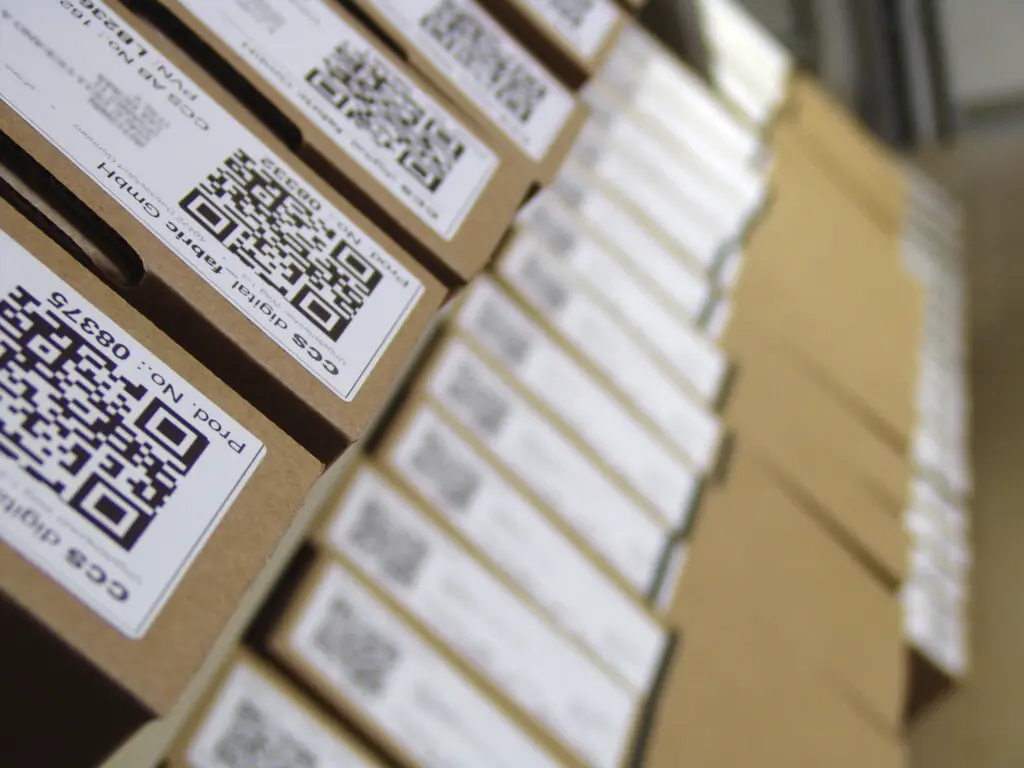 Mehrere hohe Stapel aus flachen braunen Verpackungskartons, die mit einem Versandlabel beklebt wurden