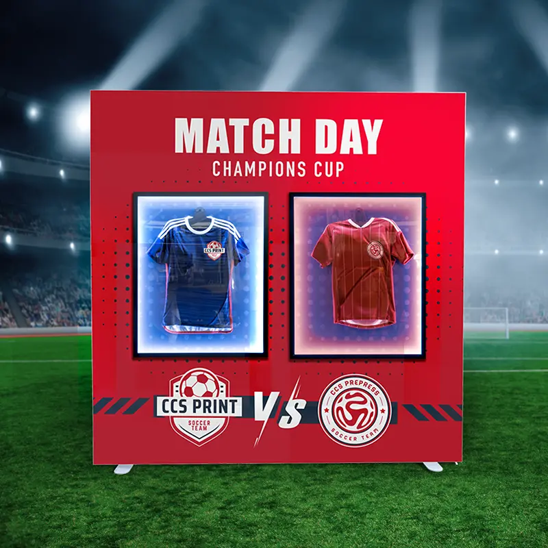 Der Game Frame: Textilspannrahmen mit 2 eingesetzten beleuchteten Vitrinen, in denen Trikots hängen, auf einem Spielfeld