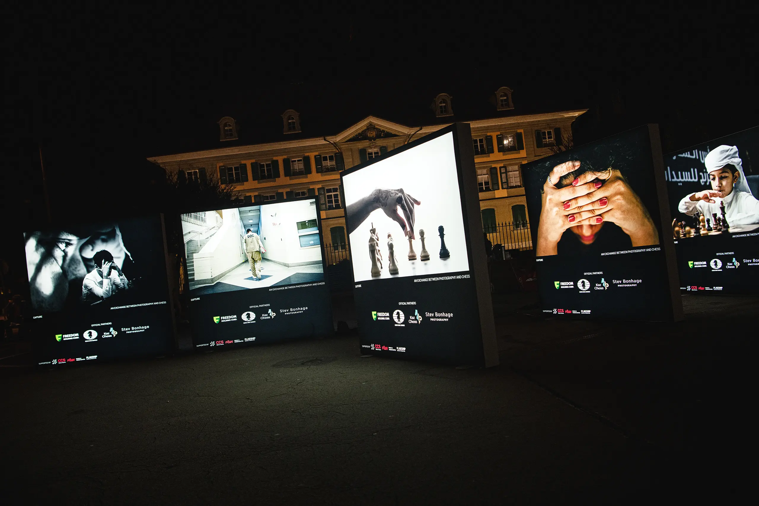 Leuchtende Textildrucke von Fotografien bei Nacht vor einem Gebäude
