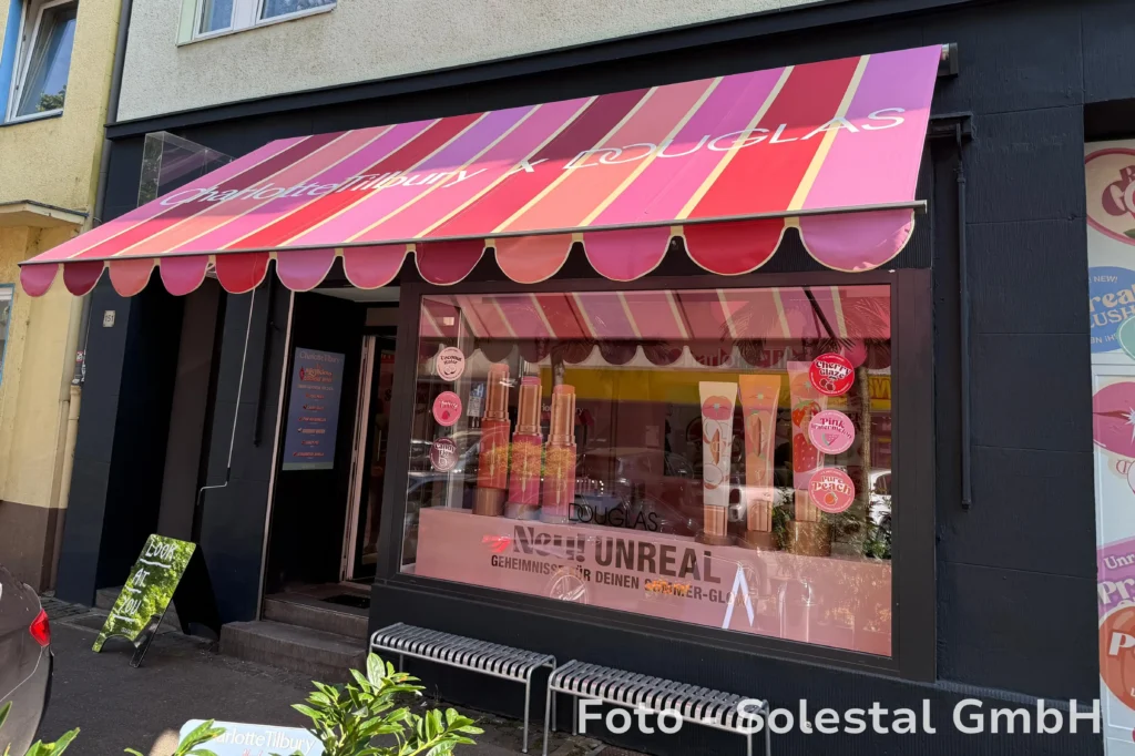 Colorful awning with Charlotte Tilbury x Douglas-Branding above the storefront of a pop-up-shop