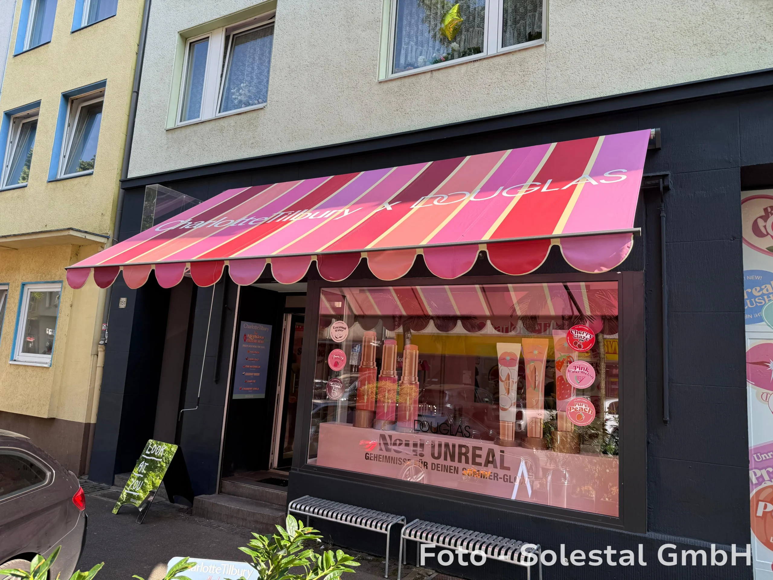 Colorful awning with Charlotte Tilbury x Douglas-Branding above the storefront of a pop-up-shop