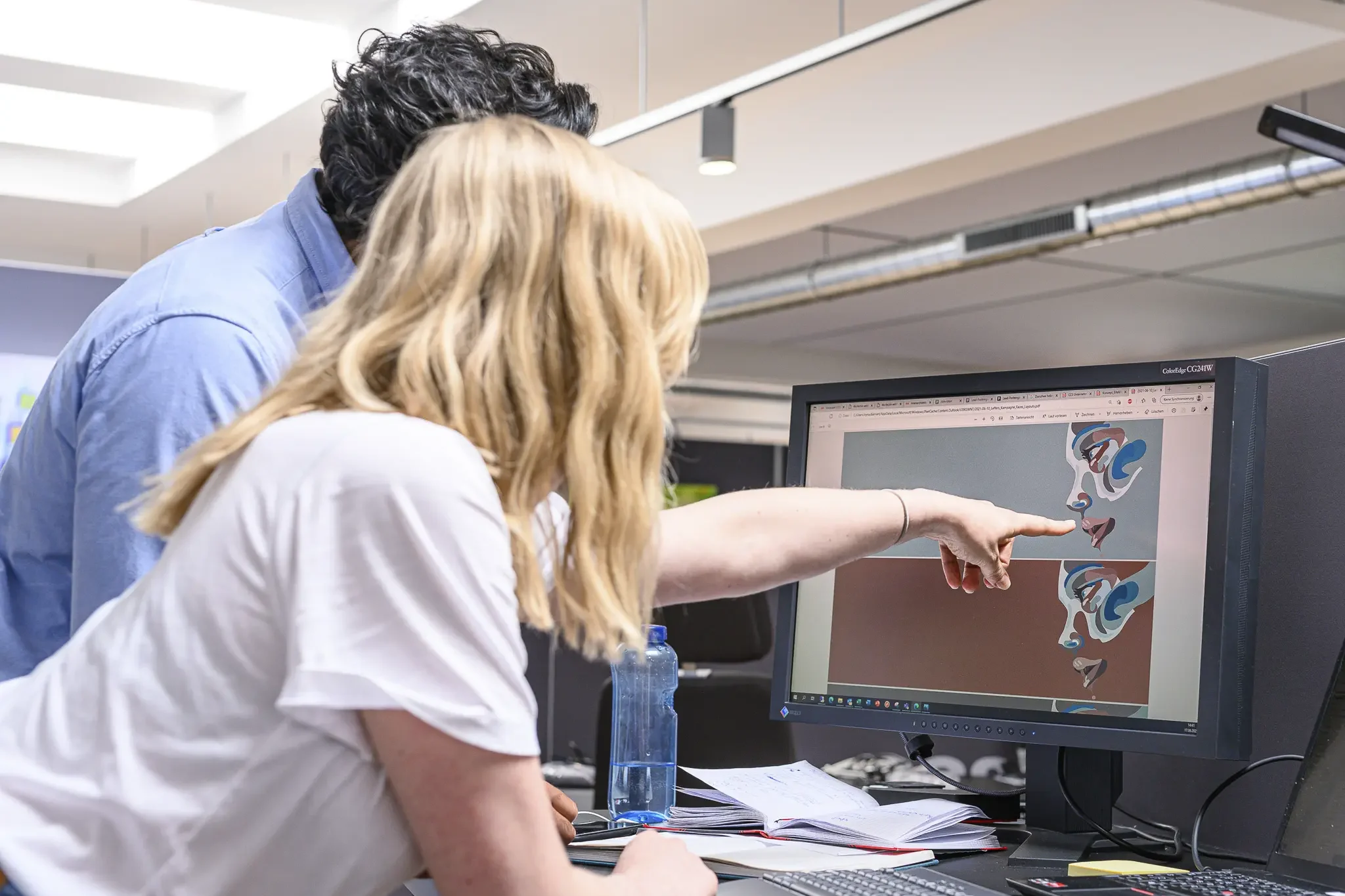 Zwei Mitarbeitende kontrollieren Druckdaten an einem Monitor im PrePress Service